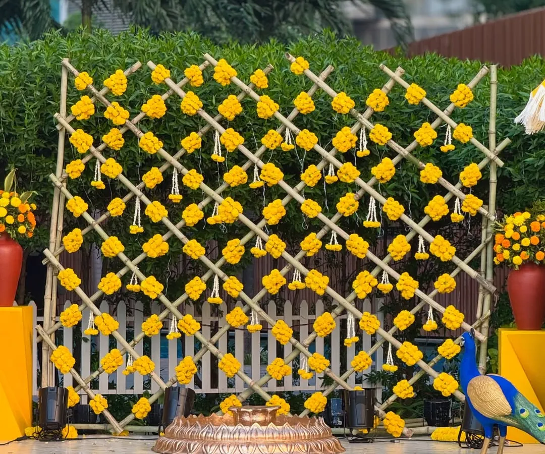 We love the classic sunshine vibe of a Haldi ceremony. Here, a custom bamboo lattice backdrop adorned with bright yellow marigolds and traditional hanging tassels creates a joyful and picture-perfect setting for the celebration.
