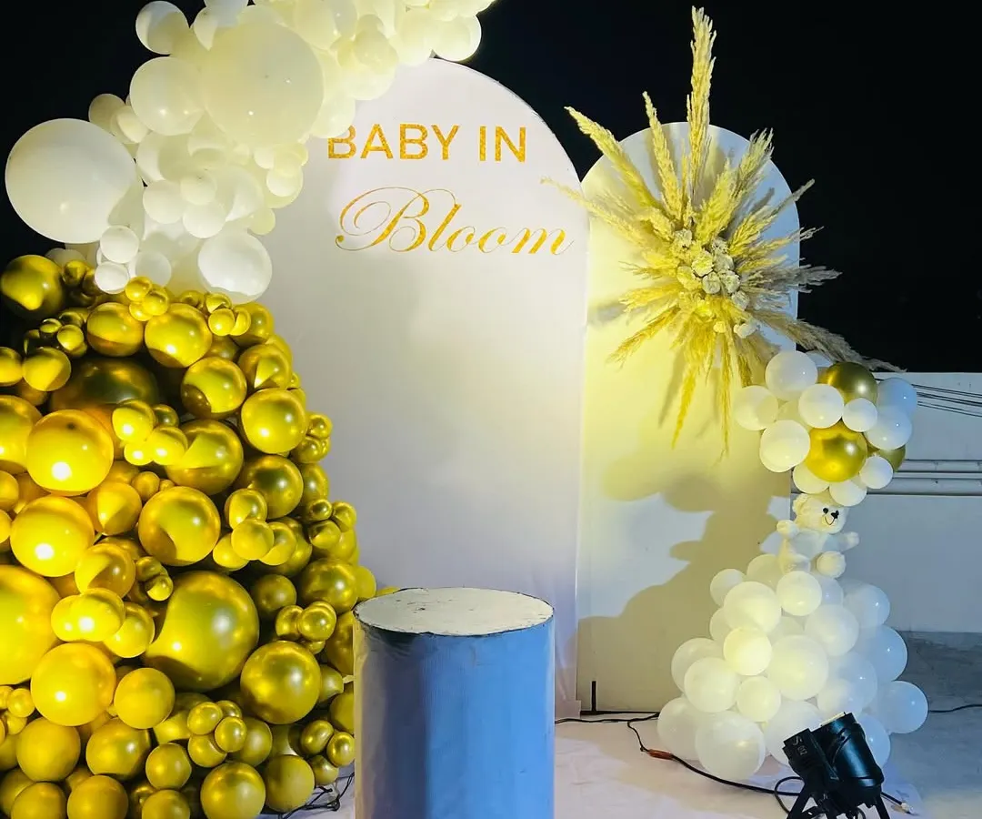 An elegant "Baby in Bloom" baby shower theme, perfect for a modern celebration. This design uses a clean white arched backdrop, a cascade of metallic gold and white balloons, and a stylish dried pampas grass arrangement for a sophisticated look.