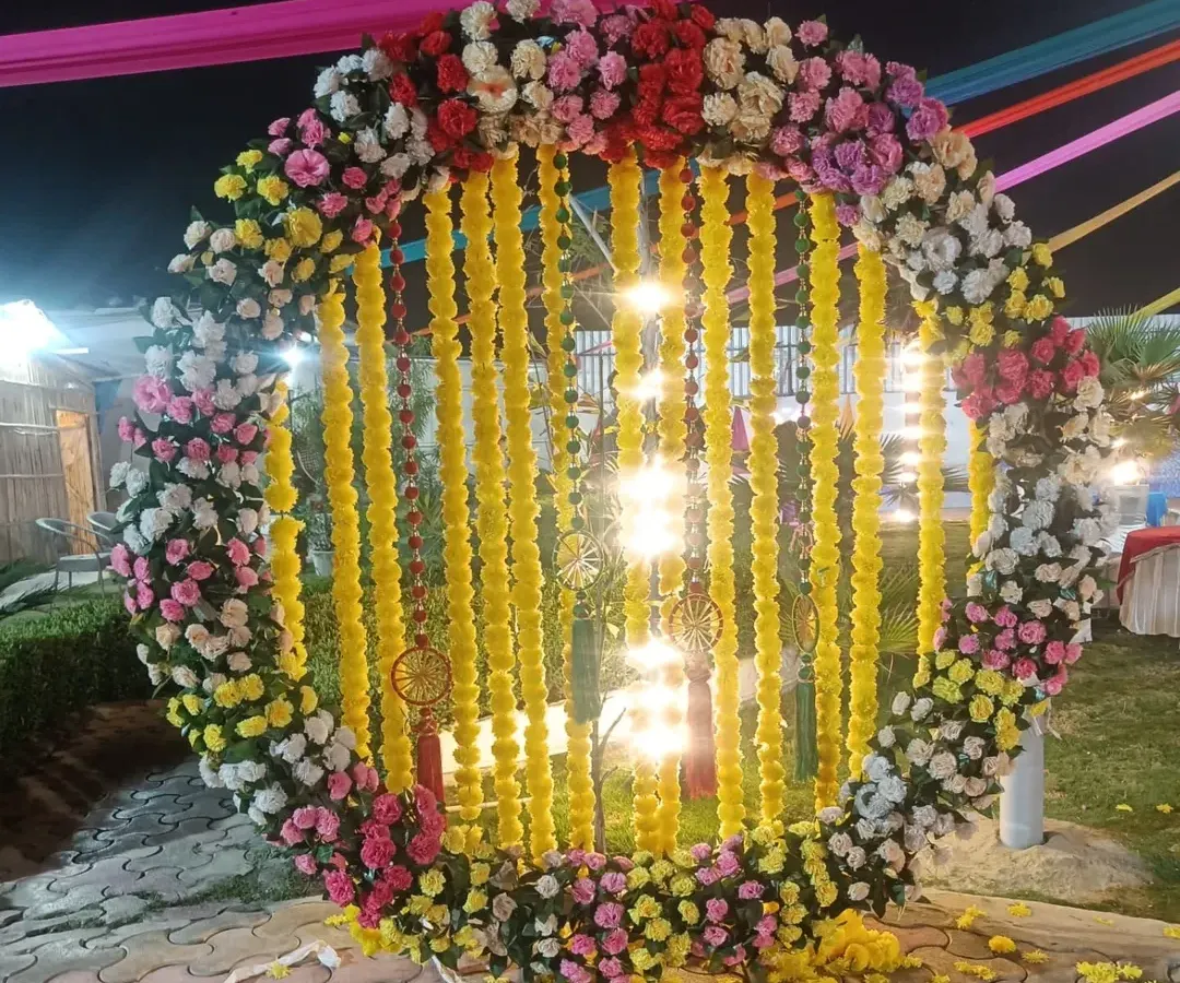 A beautiful and trendy photo booth is a must for any celebration. Here, I designed a large circular floral ring with hanging marigold garlands, creating the perfect backdrop for guests to capture memories at an outdoor festival.
