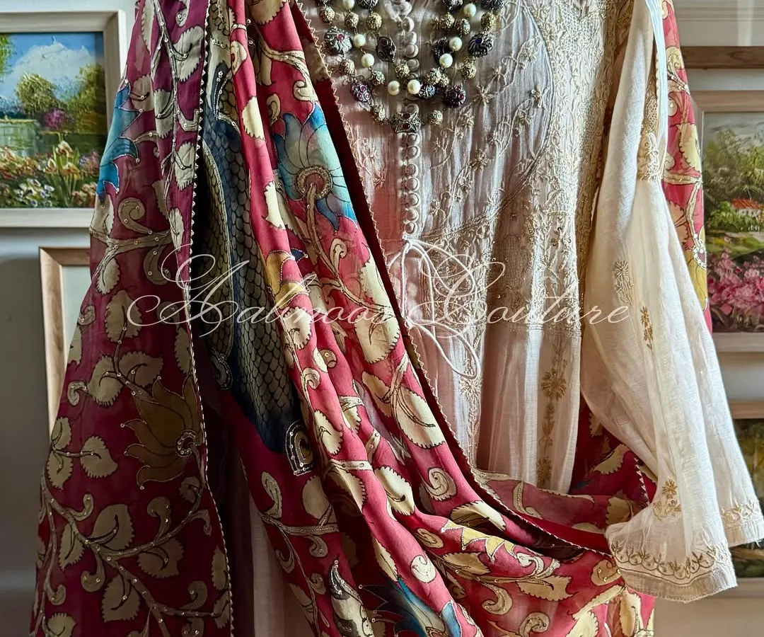 A truly regal statement, this Chikankari tissue chanderi Anarkali is draped with a magnificent Srikalahasti Kalamkari dupatta. The hand-painted peacock motifs on a deep maroon base evoke a sense of heritage and grandeur, perfect for the most special occasions.
