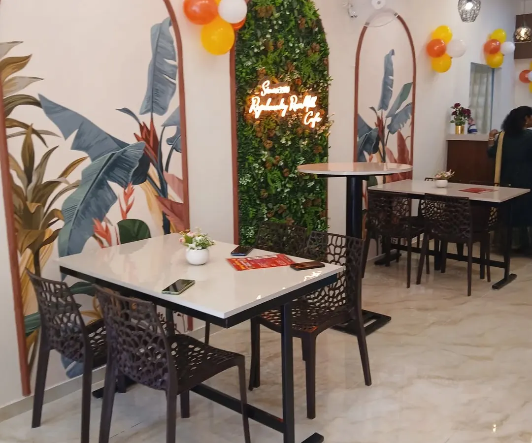 Here is the final look of the Rajarammundry Rose Milk cafe. We designed the space to feel bright and welcoming, using custom tropical murals, a vertical garden wall with a neon sign, and a mix of seating to create a cosy atmosphere for customers.