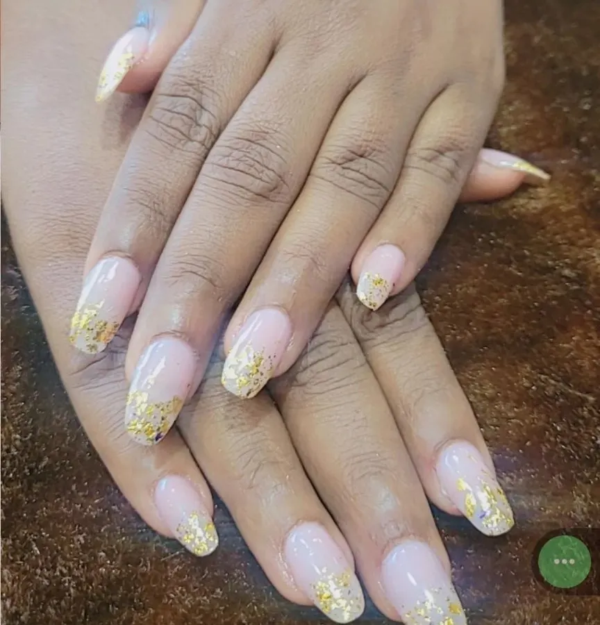 I love how these gold foil flakes look scattered over a natural nude base. This set features long, coffin-shaped nails, giving a modern and luxurious feel that I can create for you right at your home.