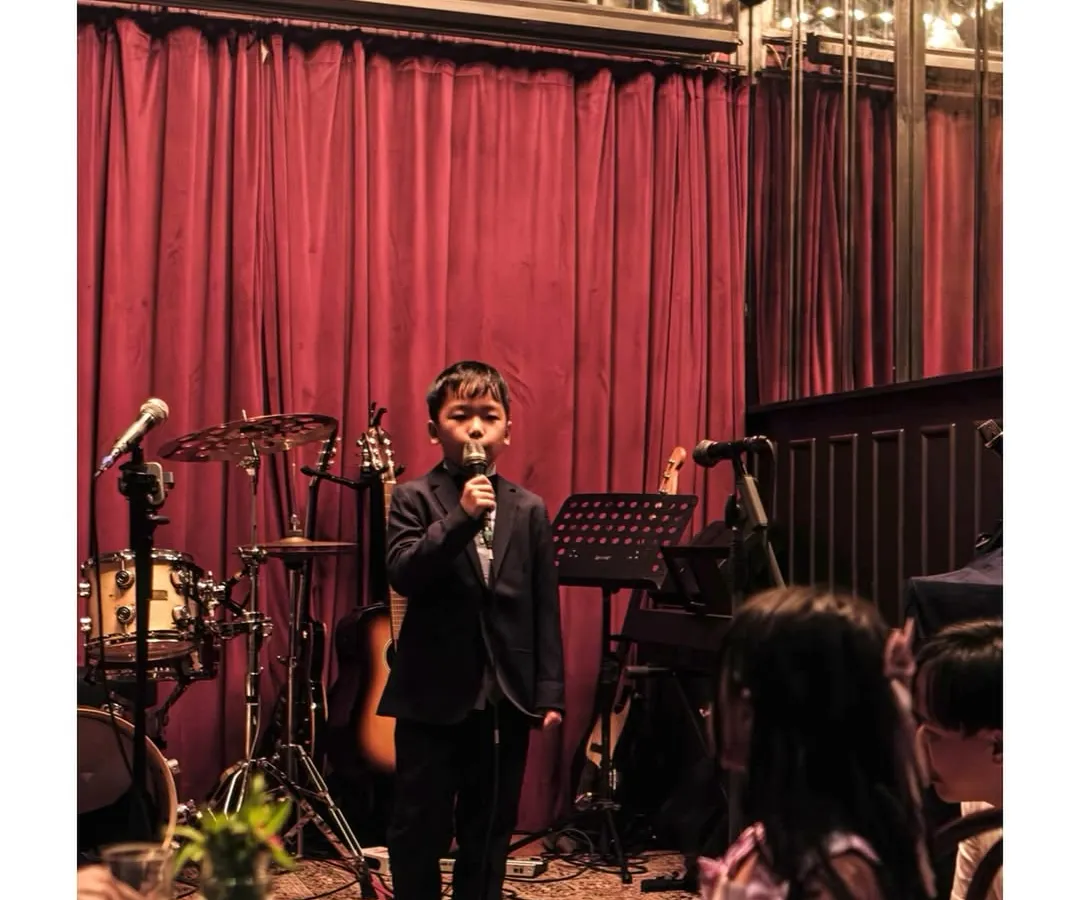 It's never too early to start your journey as a performer. Here's one of our youngest vocal students captivating the audience at a Students' Gig, showing the confidence we build from day one.