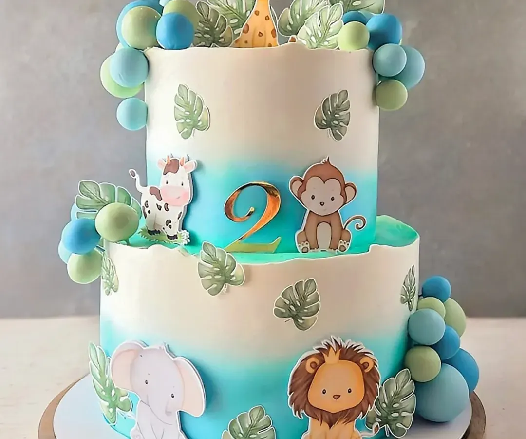 A two-tiered jungle safari cake perfect for a little one's birthday. This 4kg creation combines fresh strawberry and chocolate flavours, all covered in my signature non-fondant whipped cream. The gentle blue ombre, cute animal toppers, and handcrafted leaves bring the friendly jungle theme to life.