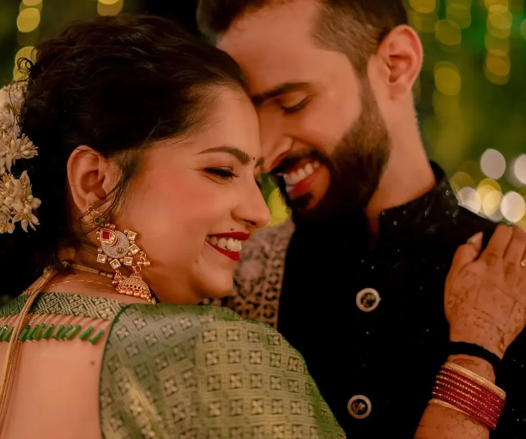 The purest joy is found in these unscripted moments. A close-up of a couple sharing a genuine, happy smile, their connection illuminated by the soft glow of celebration lights.