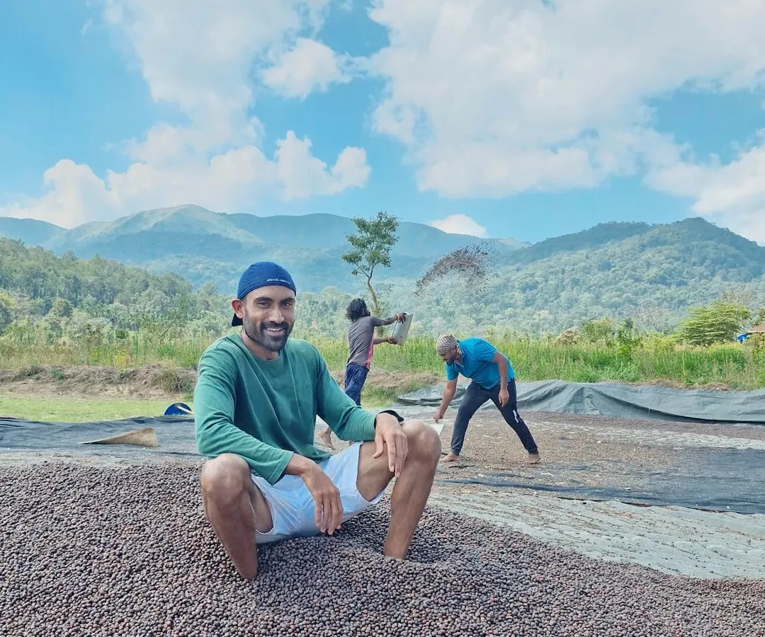 This is what hands-on looks like. I'm sitting on a fresh pile of our Robusta coffee beans as they begin the drying process, a critical step in developing their flavor. You can see the hard work happening right here, with the mountains as our constant backdrop.