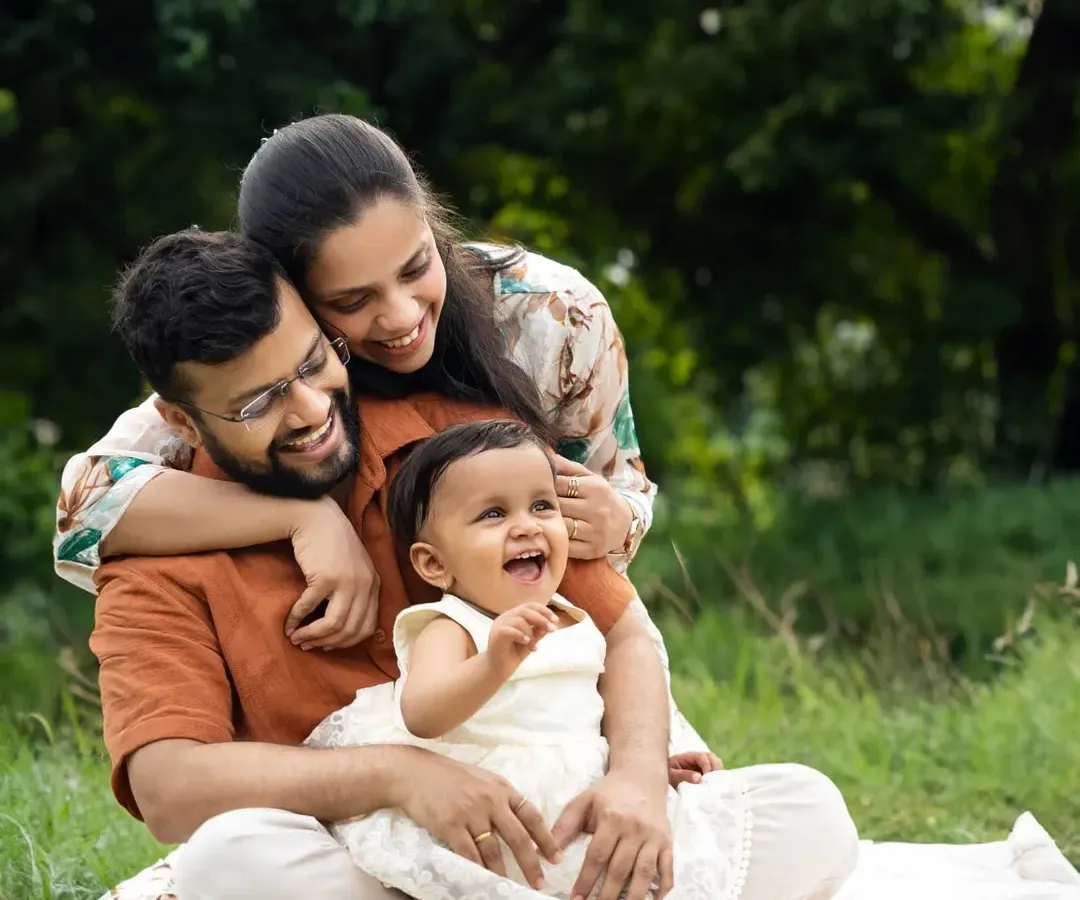 A family shares a heartfelt laugh during an outdoor session in a lush green park. Capturing these unposed, joyful moments is what makes outdoor family photoshoots in Mumbai so special.