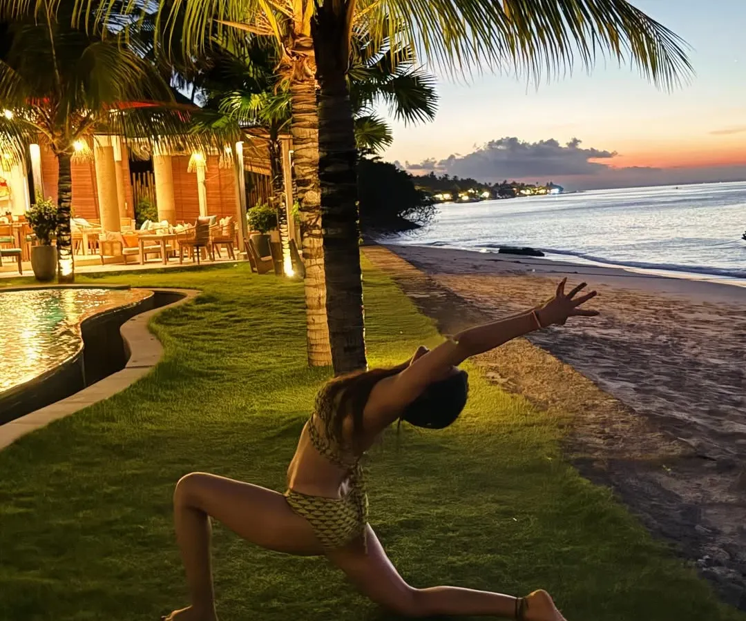 As dusk settles over the Bali coast, we find moments of peace and reflection. This gentle low lunge, performed on the soft grass by the sea, is a perfect way to unwind and absorb the energy of the ocean.