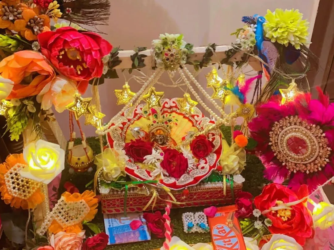 For Janmashtami, I design special jhulas (swings) for Laddu Gopal. This setup includes a decorated swing, star-shaped fairy lights, artificial flowers, and peacock feather details for a festive look.