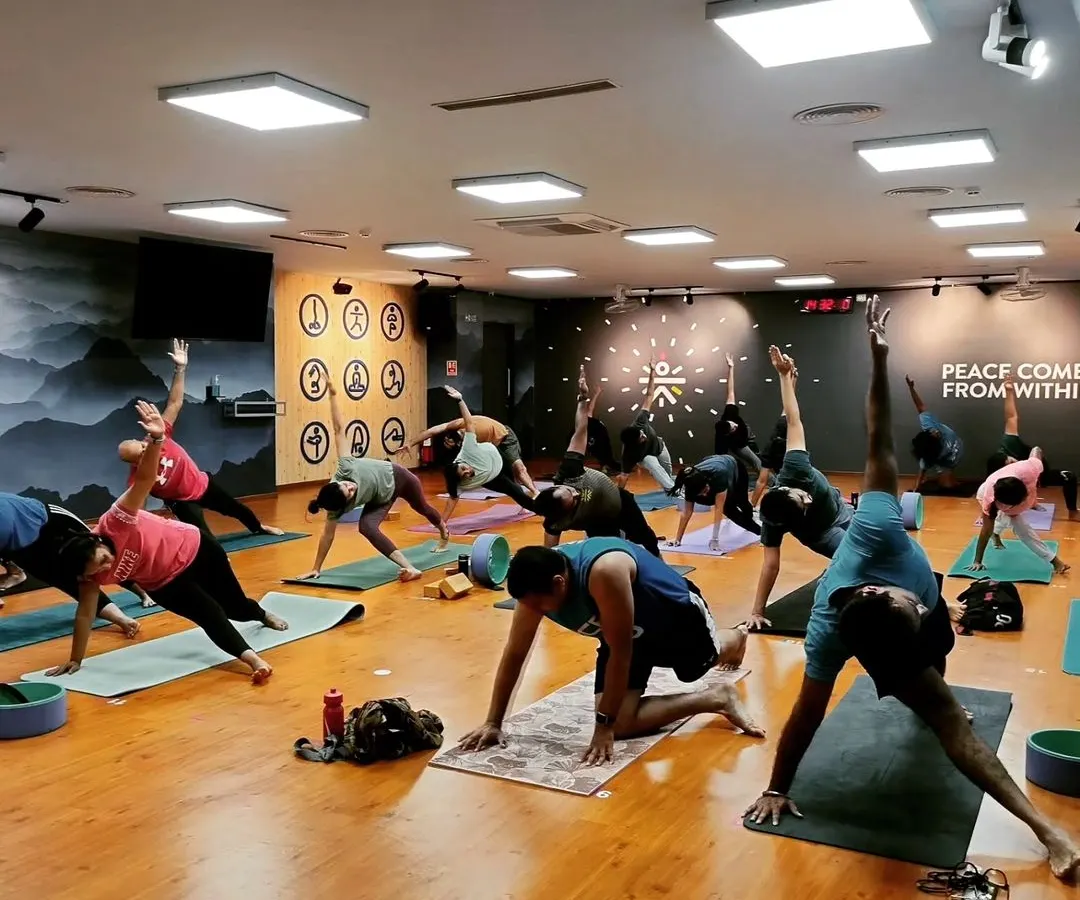 The energy in our group classes is everything. Here you can see a full studio of students moving together, each on their own journey but sharing a collective focus and strength in a Vasisthasana (Side Plank) variation.