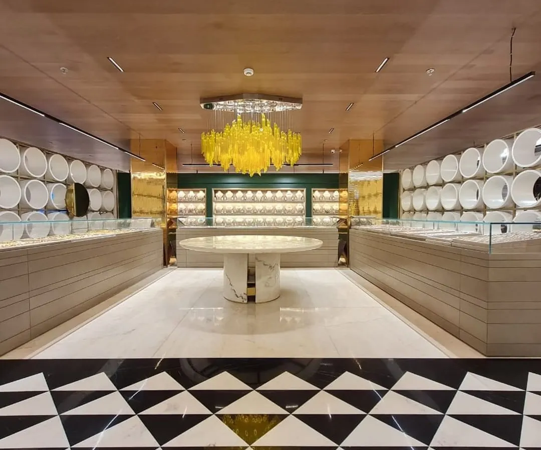 For this Ambala jewellery store, the goal was to create an atmosphere of bright, clean luxury. The lighting design balances powerful, high-quality illumination for the display cases with a stunning decorative centerpiece, a custom yellow chandelier that adds a bold, artistic statement to the retail environment.