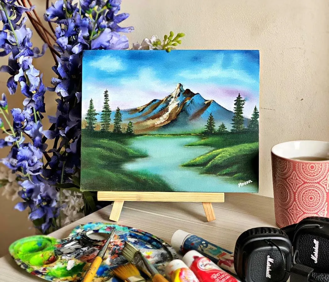 A finished landscape painting, capturing a quiet moment in nature. In my classes, I teach how to use acrylics to create depth and atmosphere, turning a blank canvas into a window to another world. All the supplies you see here are what we use in our sessions.