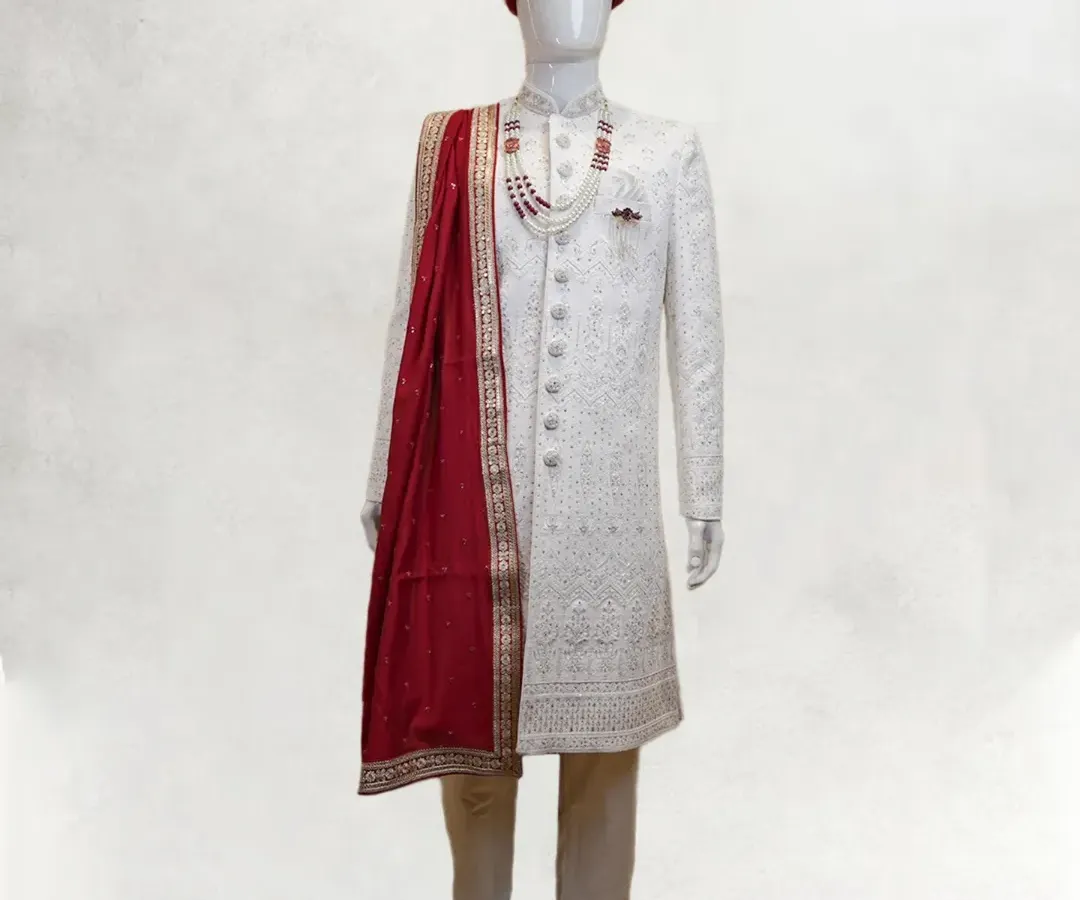 The quintessential royal groom's attire. This is my classic all-white, intricately embroidered sherwani, perfectly complemented by a rich maroon stole and a matching turban for a look of timeless elegance on your wedding day.