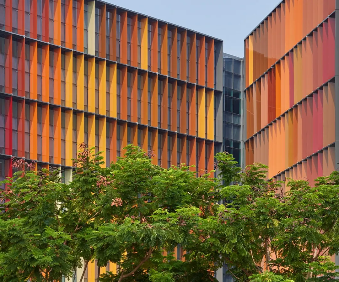 For the Infosys Campus in Nagpur, we designed a dynamic facade with colourful fins that are not merely aesthetic. Each fin is precisely angled to provide solar shading, reducing heat gain and glare, which significantly lowers the building's reliance on air conditioning and creates comfortable, naturally lit workspaces.