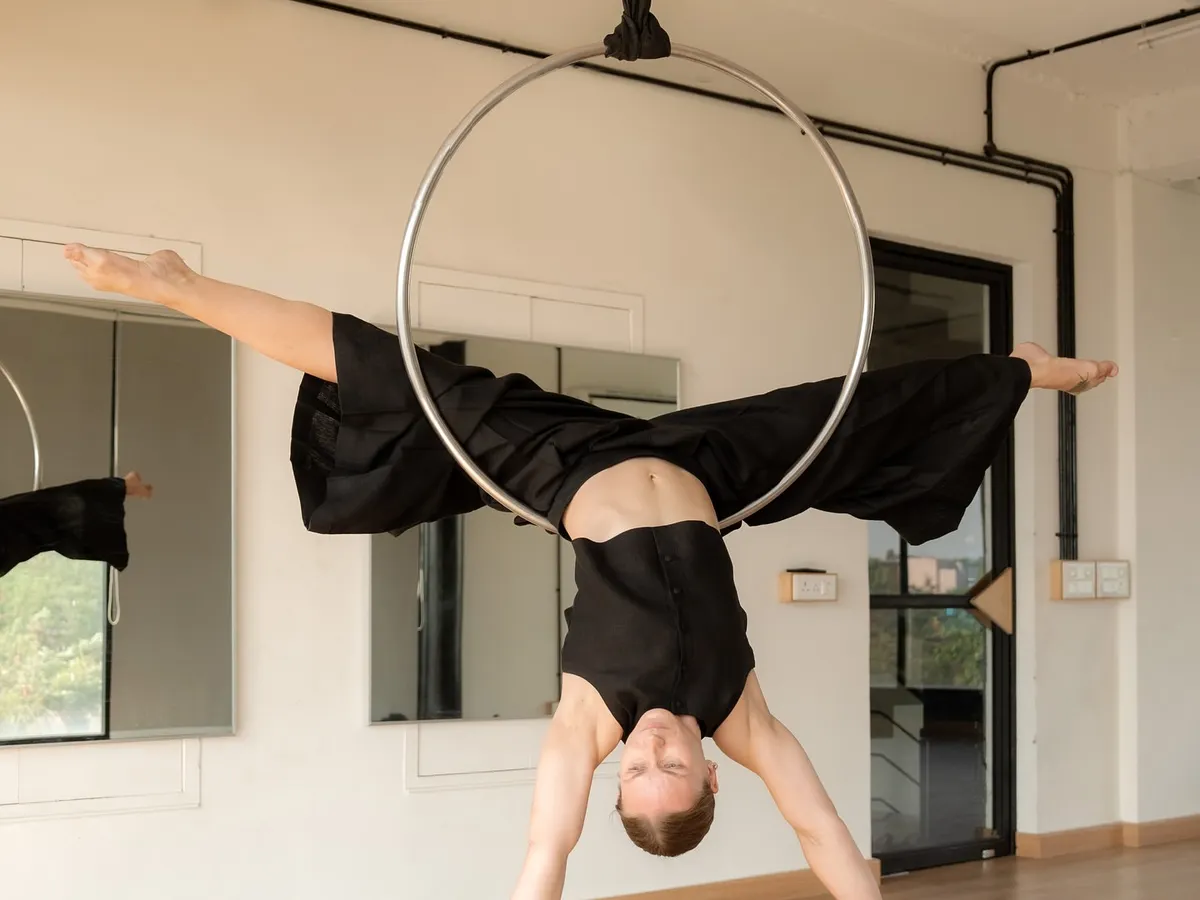 A moment of stillness on the aerial hoop, or lyra. This pose, a variation of a split, showcases the blend of artistry and athleticism that makes this apparatus so captivating. It’s a beautiful example of aerial performance photography.