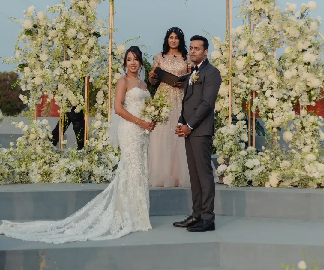 A pristine and elegant Christian wedding ceremony, with the couple standing before a beautiful floral arch of white hydrangeas and roses. I specialize in creating sophisticated and modern wedding aesthetics.