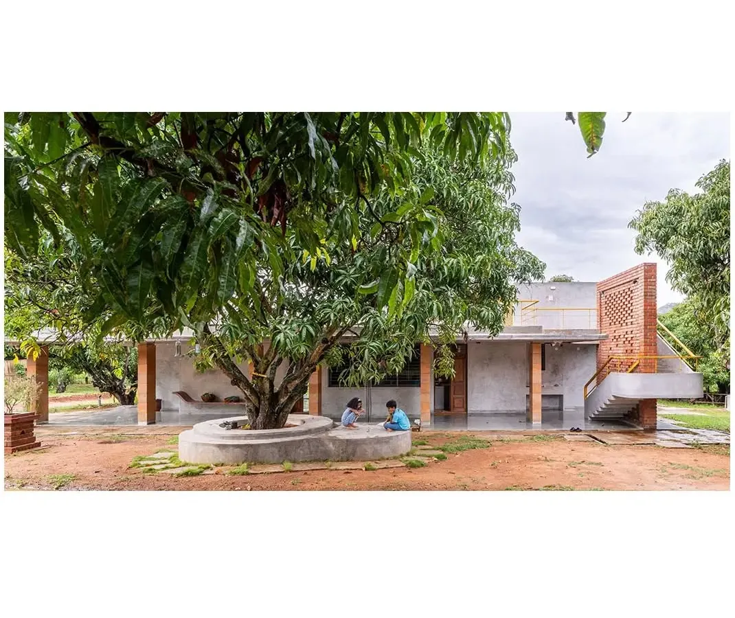At the 'Aamra' farmhouse, life unfolds around a mature mango tree, which serves as the heart of the home. The design prioritizes the existing landscape, creating a built form that respects and integrates with the natural environment, offering spaces for quiet contemplation and family life.