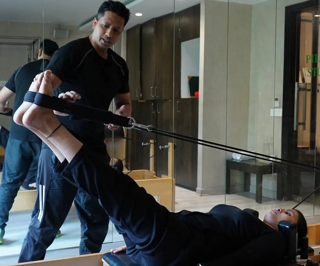 I believe in hands-on guidance. Here, I'm helping a client perfect her leg press form on the reformer, ensuring she engages the right muscles for maximum benefit and injury prevention.