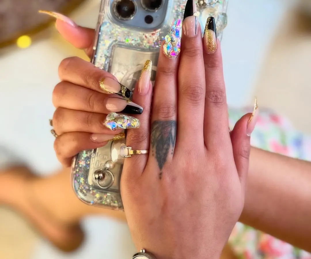 For those who dare to be bold, we create stunning 3D nail art. This dramatic look features long, sculpted extensions with a mix of glossy black, shimmering gold, and a statement nail covered in multifaceted crystals for maximum impact and sparkle.