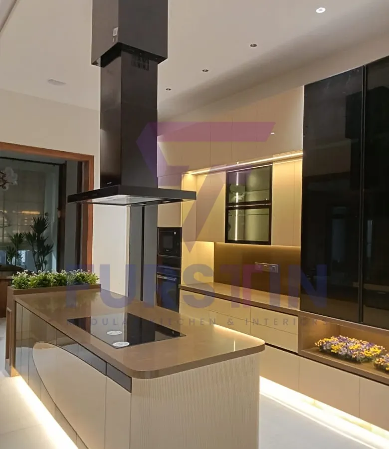 This is the centerpiece of our Bharatpur island kitchen project. The sleek island features an integrated hob and provides ample counter space, while the suspended chimney adds a modern, sculptural element. We used a combination of high-gloss laminates and warm wood tones, complemented by strategic under-cabinet and kick-plate lighting to create a luxurious and inviting atmosphere.