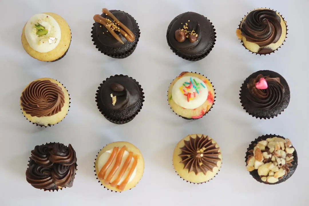 A top-down view of my TBC Minis, showcasing the variety of flavours and designs available in a single assorted box. From Kesar Badam Pista to Nutty Chocolatey, each bite-sized cupcake is a unique experience.