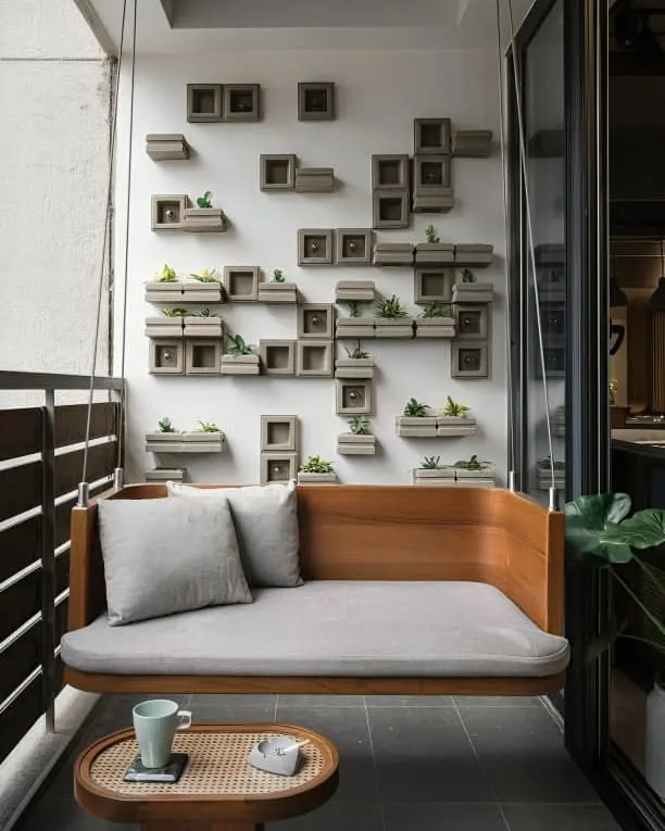 A custom-designed wooden swing bench provides the perfect spot for morning coffee or quiet reading. This piece combines comfort with a clean, modern aesthetic, complemented by a unique wall-mounted planter system for a touch of minimalist greenery.