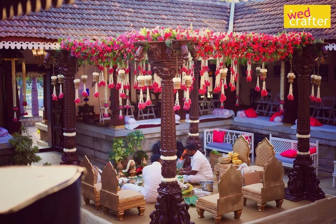 I have a special love for heritage venues. Here, we designed a traditional mandap with antique wooden pillars and vibrant bougainvillea, perfectly complementing the timeless charm of a 240-year-old Thottimane.