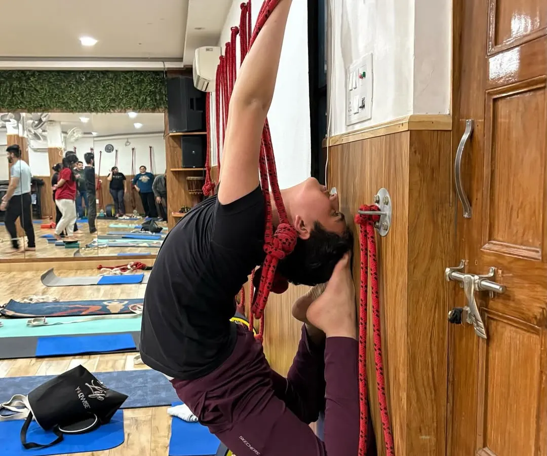 Advanced poses like this deep backbend become accessible with the right tools and guidance. We use wall ropes and a yoga wheel to support the spine, allowing you to open your heart and build flexibility with confidence.