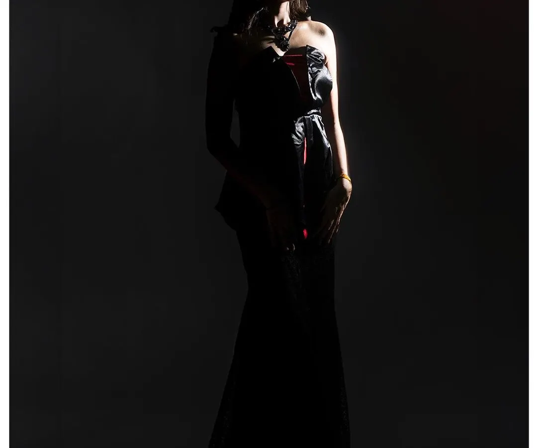 I love playing with shadows to create mood and drama. For this shot, I used a single light source to sculpt the model's silhouette against the dark background, emphasizing the form of the gown and creating a powerful, cinematic feel.