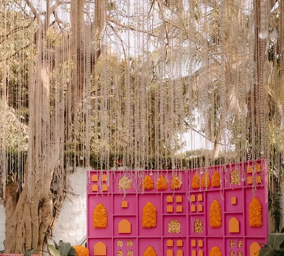 This Mehandi backdrop was all about making a statement. We designed a vibrant pink grid wall, filling it with bright orange and yellow marigold arrangements and adding a curtain of delicate hanging flowers for a touch of magic.
