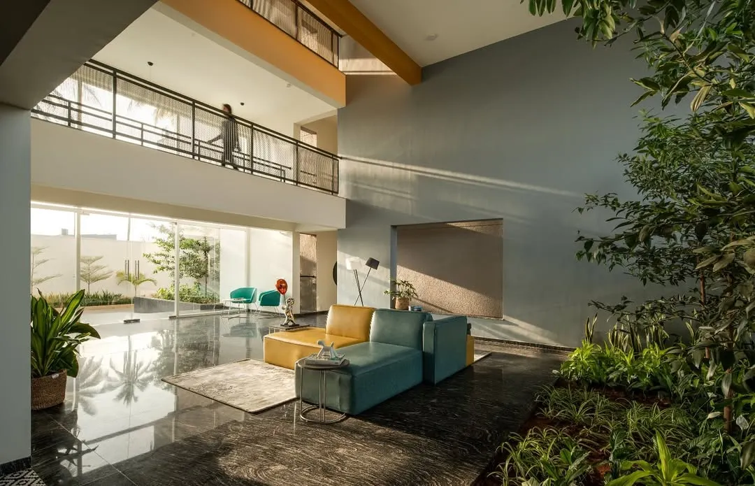 The double-height entrance lobby of 'The Treehouse' apartments is designed to maximize natural light and create a welcoming, open atmosphere. We integrated lush indoor planting and contemporary furniture to blur the line between the interior and the surrounding landscape, establishing a serene arrival experience for residents.