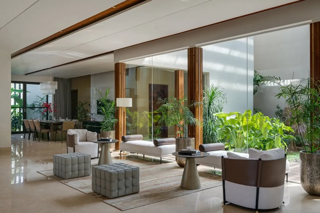 In our Celadon farmhouse project, the formal living area flows effortlessly into a central lounge and an open-air courtyard. This design choice maximizes natural light and fosters a constant connection to the lush greenery, embodying our principle of blurring the lines between inside and out.