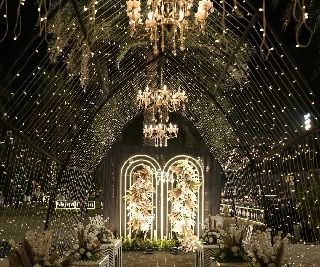 This is how I turn a sangeet night into a celestial dream. A grand tunnel entrance adorned with thousands of fairy lights and elegant chandeliers guides guests into a starry night themed celebration, promising an evening of wonder.