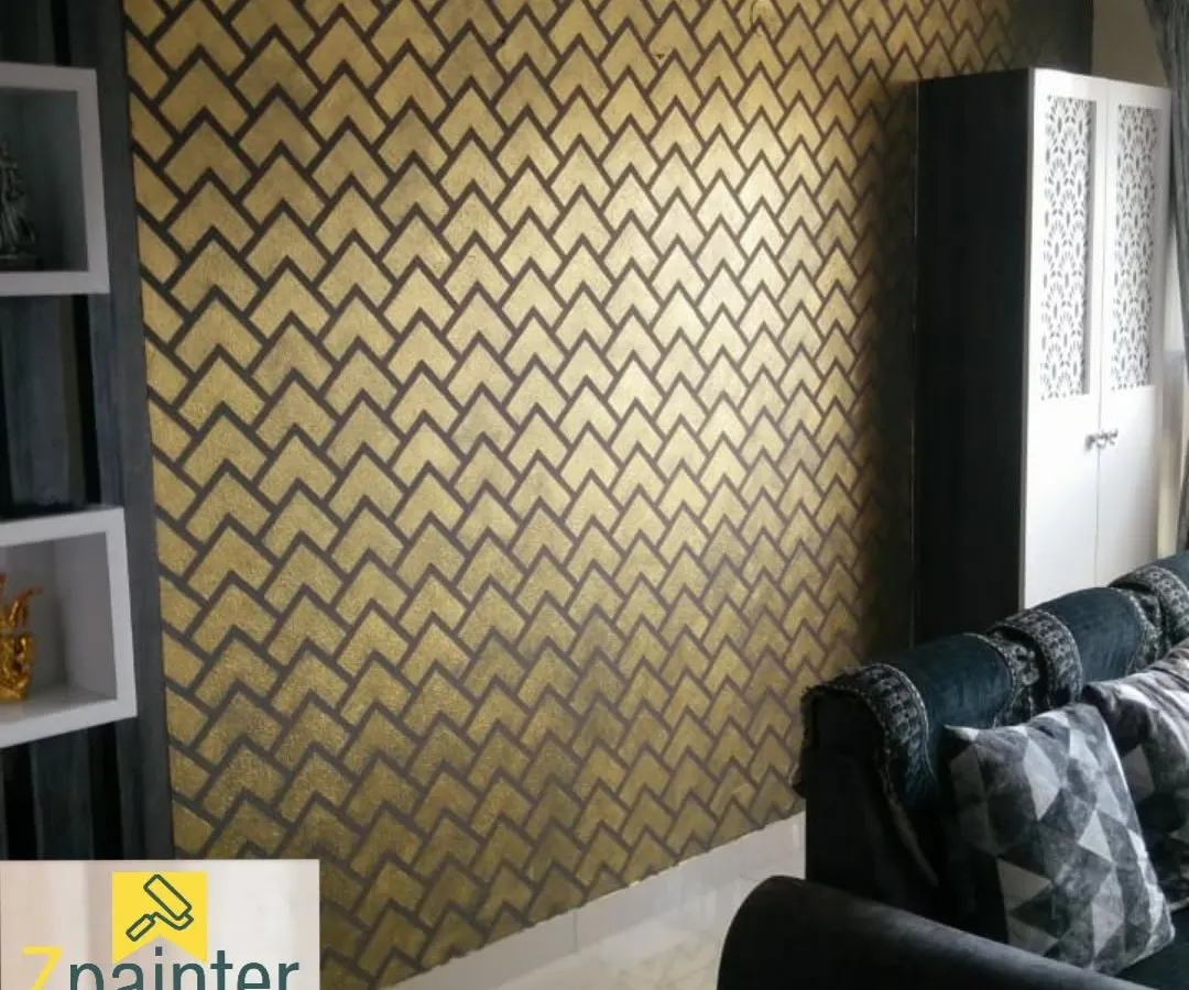 A modern living room accent wall featuring a metallic gold and charcoal grey geometric herringbone pattern. This textured design adds a touch of glamour and sophistication, catching the light beautifully.