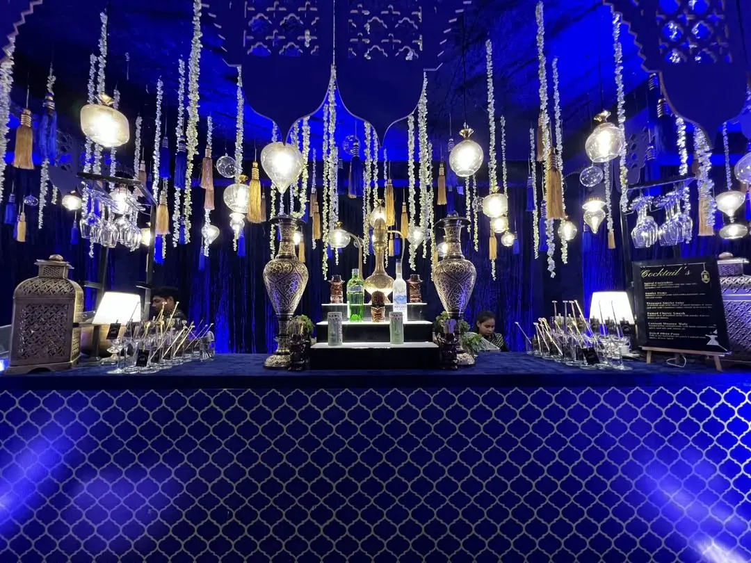 We transformed this space into a mystical Sufi night. The bar features a deep blue color palette, intricate latticework, and dozens of hanging lanterns and traditional brass surahis to create a magical, ambient glow.