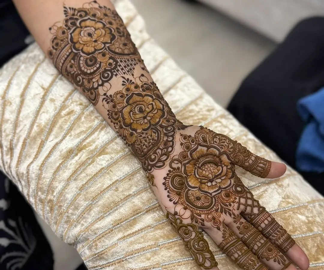 This is a classic Arabic floral henna design, perfect for festive occasions. The pattern flows from the forearm down to the fingers, featuring large, shaded roses and leafy vines with plenty of open skin for a bold contrast.