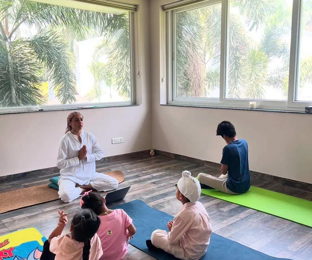 This is what my kids' yoga sessions are all about: playful movement and happy smiles. I guide a small group of children, including one in a fun scorpion-like pose, creating a warm and interactive space for mindful movement for kids.