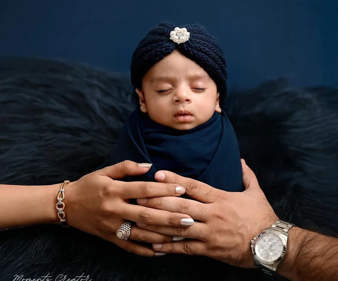 A tiny prince held safely in his parents' hands. This iconic newborn portrait captures the overwhelming love and protection that surrounds a new baby. It's a simple, powerful image that families will treasure forever.