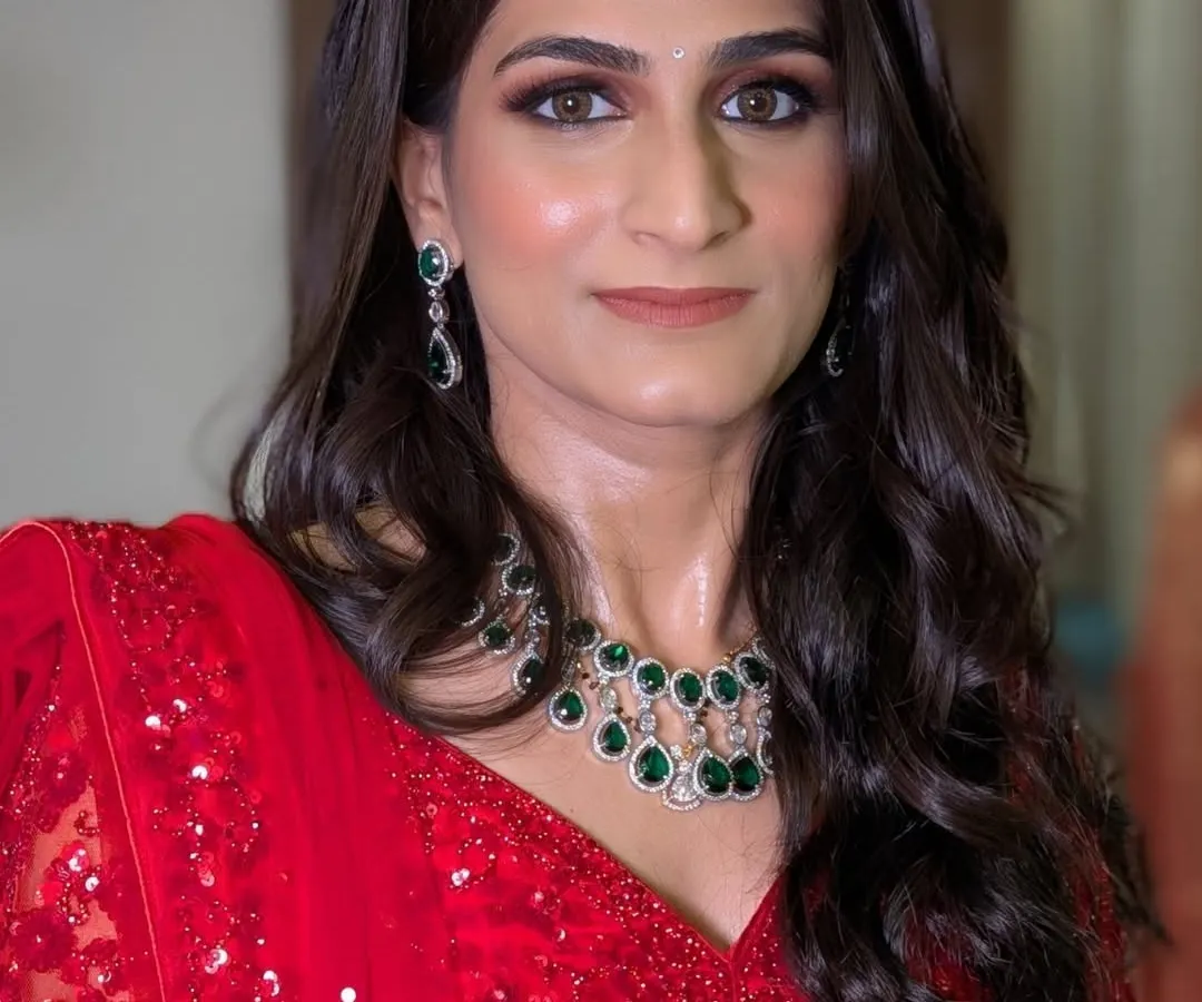 For Shriya's reception, we went for a classic and glamorous look. This features a sharp, brown smokey eye and radiant skin that looks stunning both in person and on camera, perfectly complementing her vibrant red lehenga and emerald jewellery.