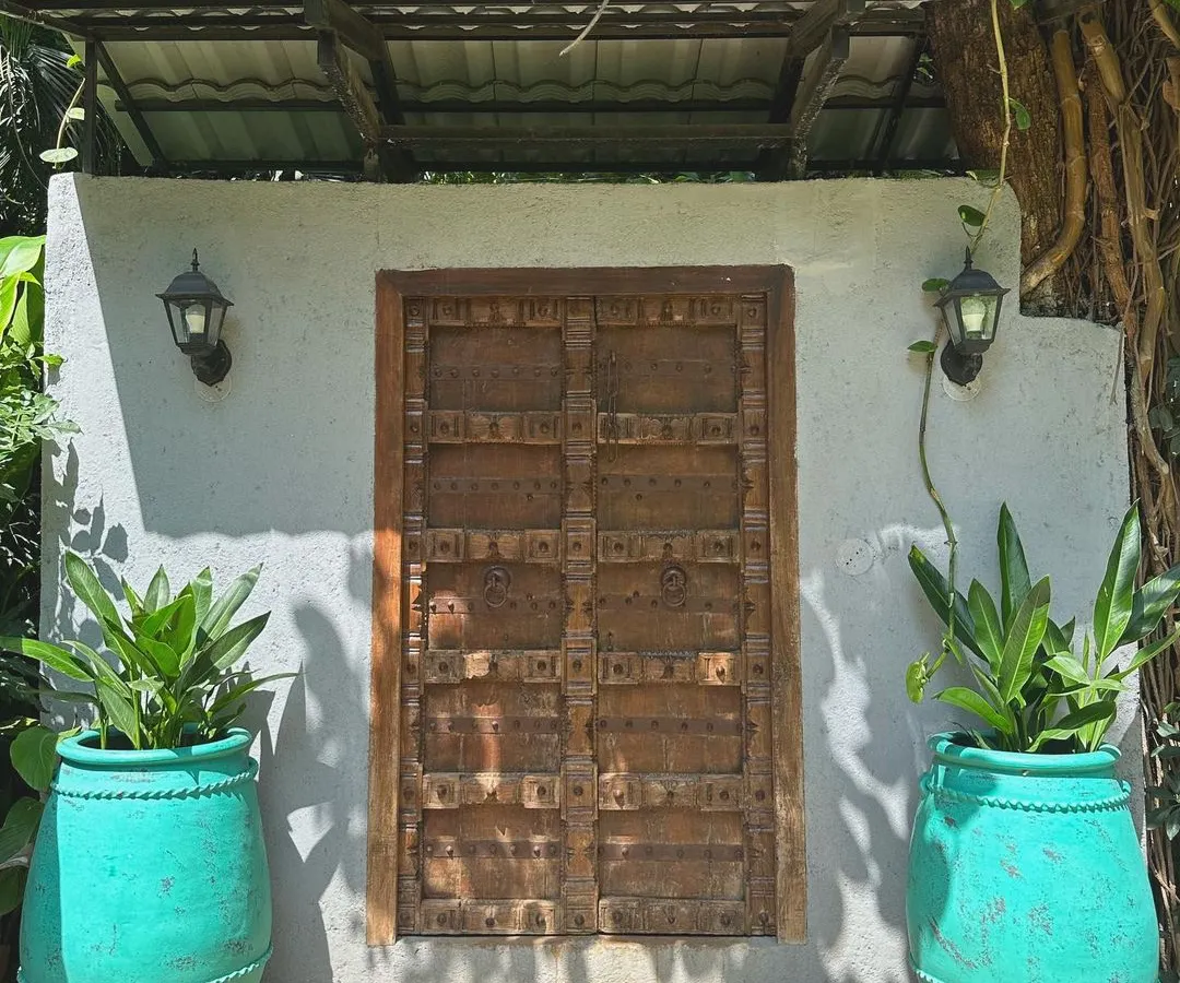 Make an entrance that tells a story. Our antique-finish terracotta 'Ubud' planters add a vibrant pop of turquoise, beautifully framing this rustic wooden door and creating an unforgettable welcome.