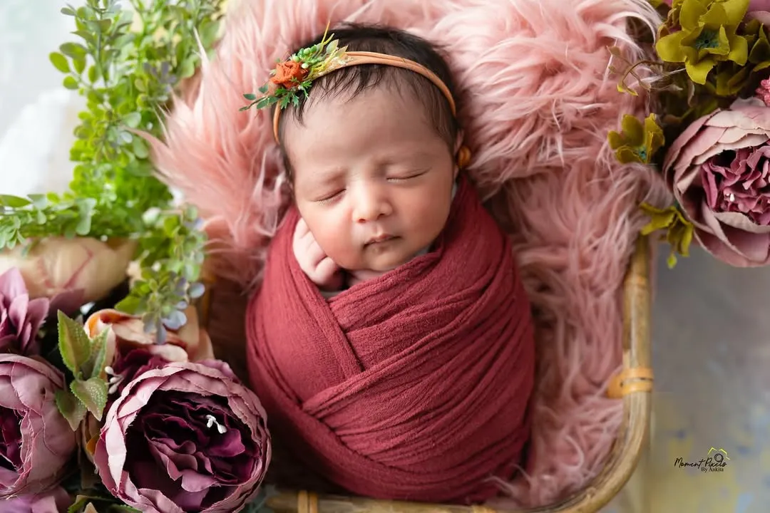 There is nothing more precious than a sleeping newborn. I specialize in safe newborn posing, and this little one, nestled among flowers in a deep red wrap, shows the peaceful, dreamy art we can create in those first few weeks.