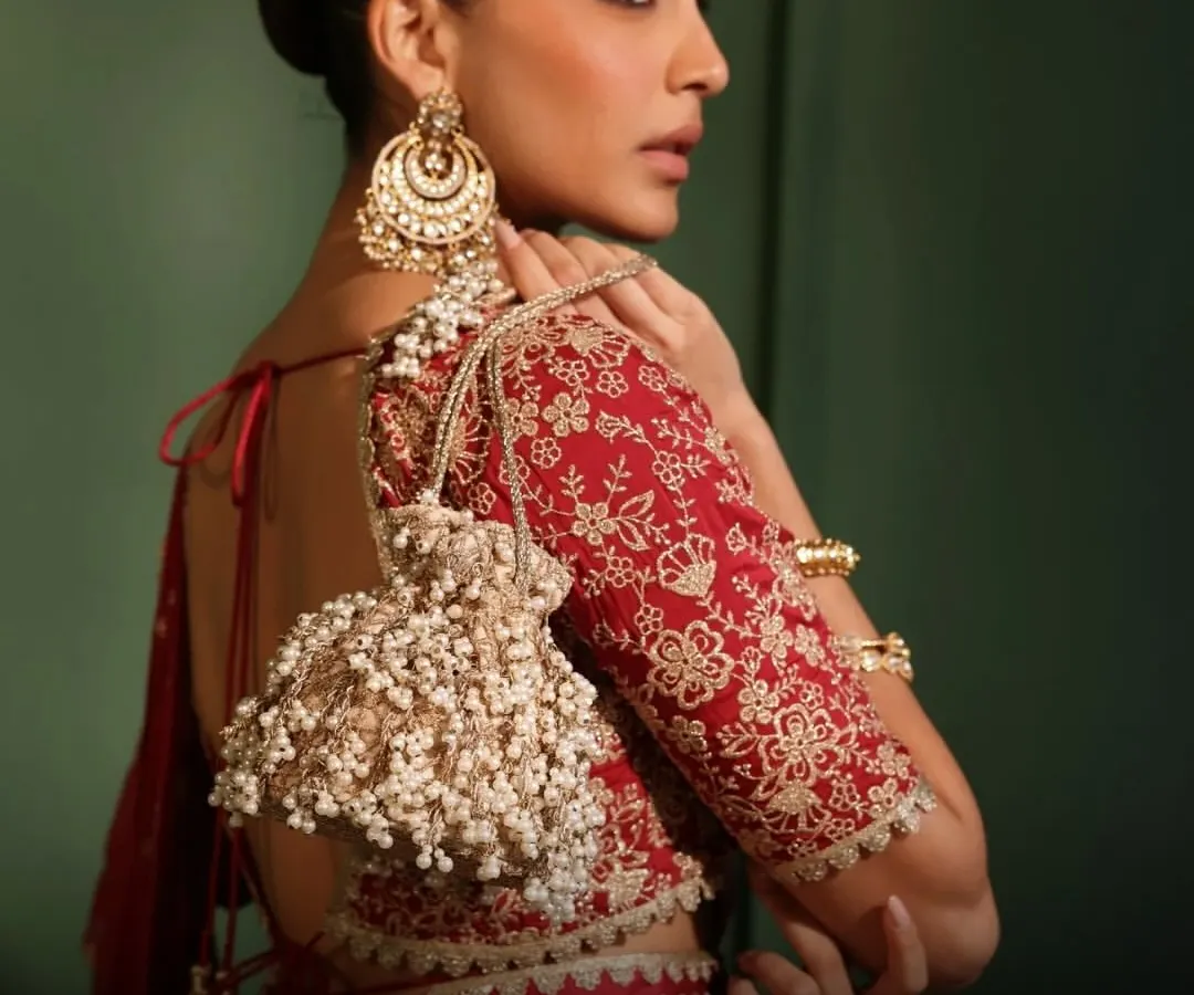 It’s all about the finishing touches. This handcrafted potli bag, with its cascading pearl tassels and delicate embroidery, is the perfect statement piece to elevate your festive saree or lehenga for a wedding reception or Diwali party.