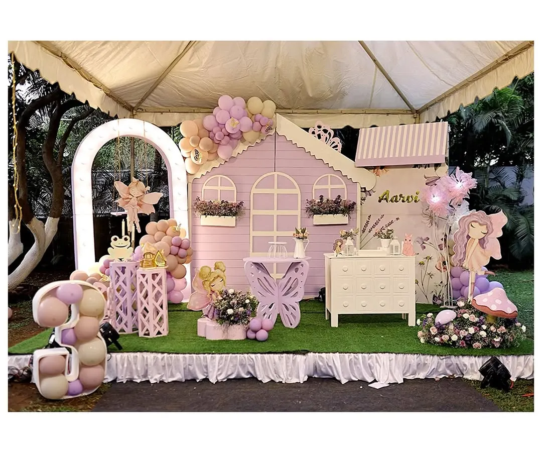 Welcome to a fairy's dream home. This enchanting setup for a third birthday features a life-sized pastel purple playhouse, a custom butterfly-shaped table, and a glowing number '3' filled with balloons, creating a magical atmosphere for the little ones.