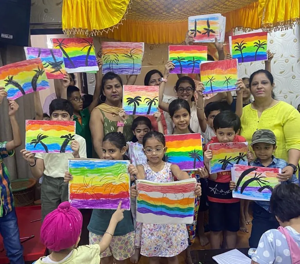 The pride on their faces says it all. Here, our young artists proudly display their colorful rainbow paintings, a beautiful result of our hands-on art workshops where we encourage every child to express their unique vision.