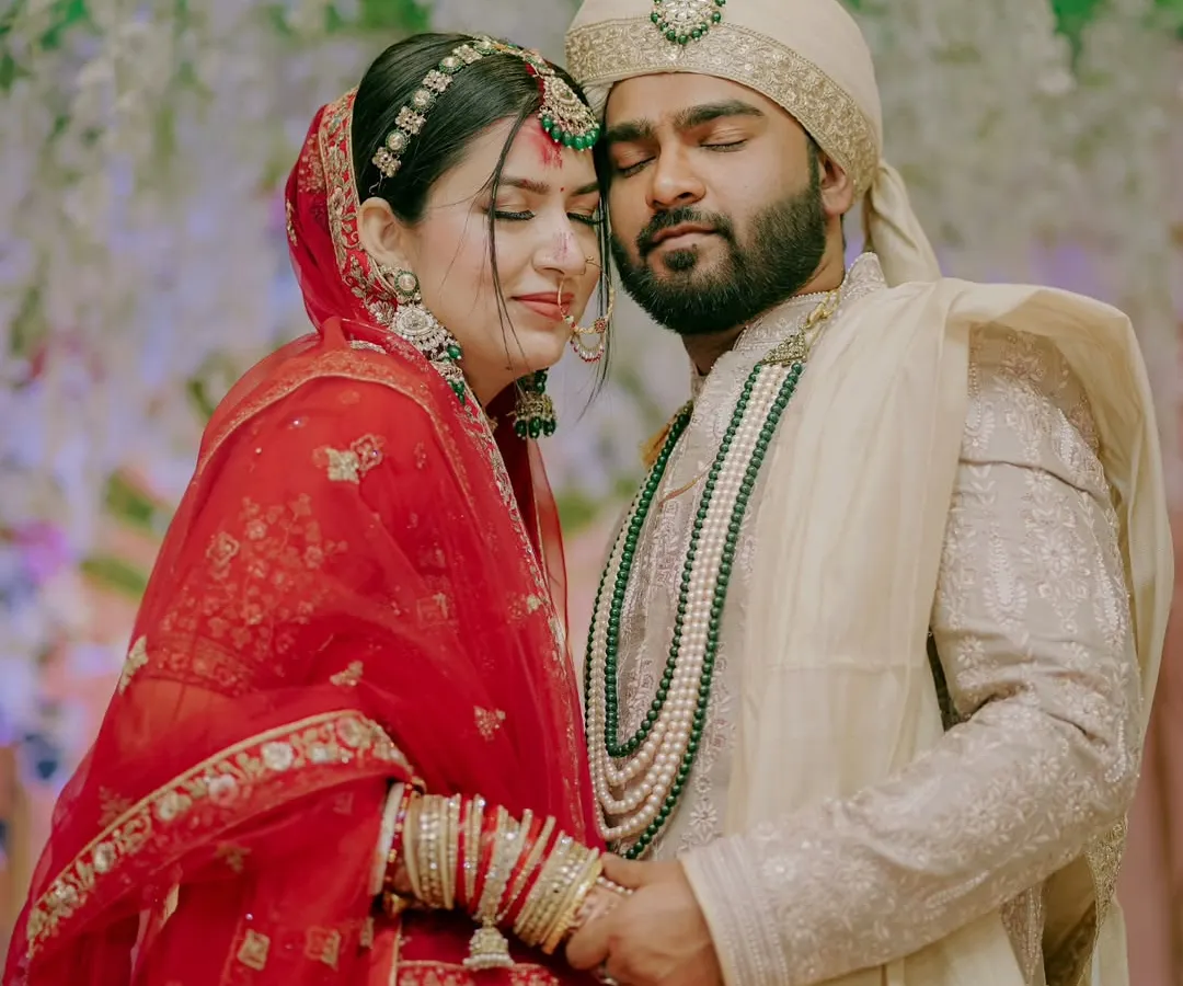 An intimate portrait of a North Indian couple, holding each other close. The rich red of the bride's lehenga and the groom's elegant sherwani create a timeless image of love and commitment.