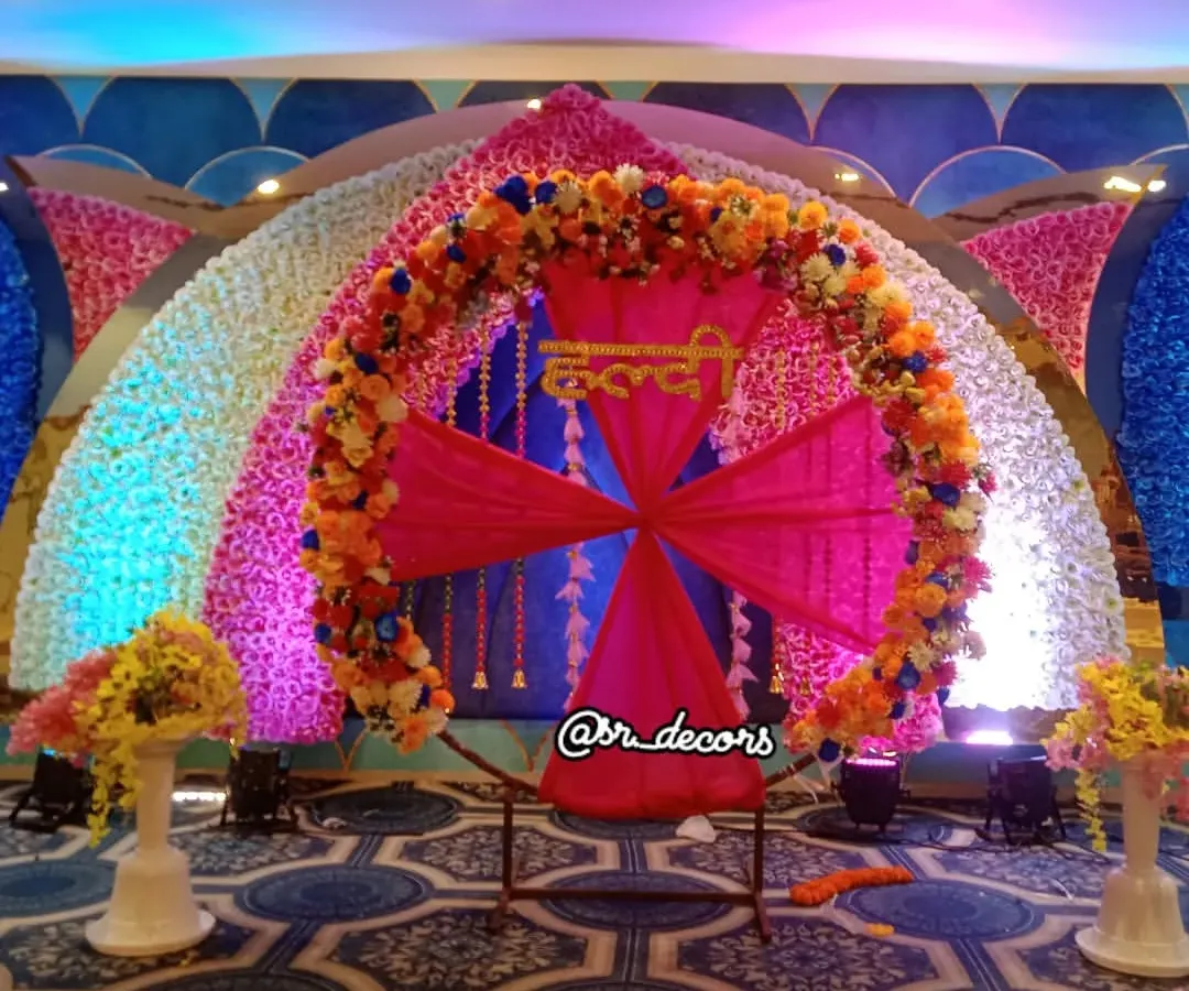 For a grand Haldi function, I can create a stunning stage like this one. It features a massive floral ring, a backdrop of flower walls, and a central seating area, making it the perfect spot for all your ceremonies and photos.