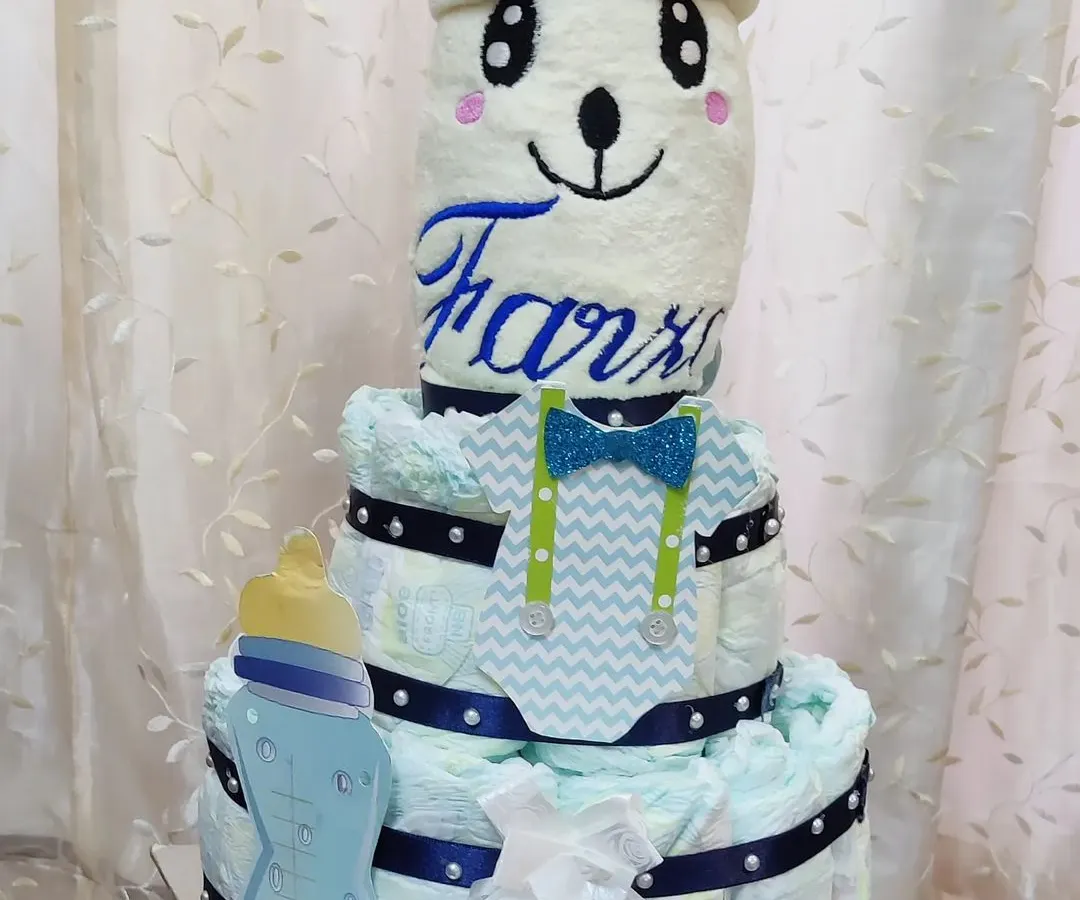How cute is this diaper tower for a new baby boy? It’s a creative and practical gift for a baby shower, built with diapers and topped with a cozy blanket embroidered with the baby's name.