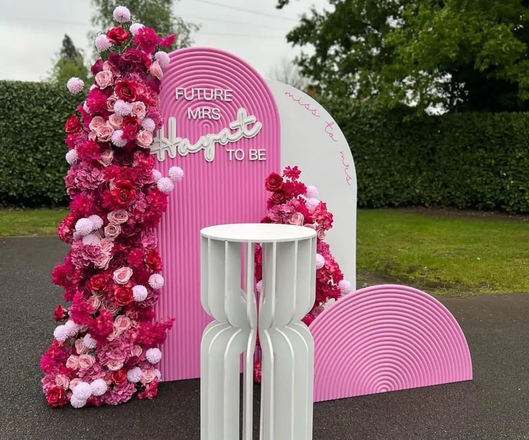 A fun and vibrant bachelorette party backdrop inspired by the popular Barbie theme. This setup includes custom pink arched panels, floral arrangements, and a 'Future Mrs' neon sign for the bride-to-be.