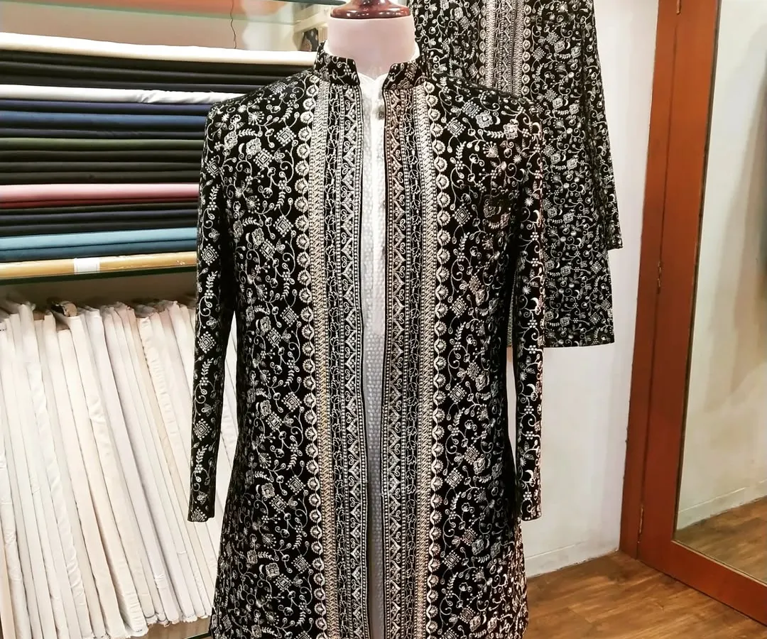 This is a showcase of our traditional craftsmanship. A black and silver embroidered sherwani, designed for a groom, displayed on a mannequin to highlight the detailed brocade work and elegant silhouette. This piece is perfect for a grand wedding ceremony.