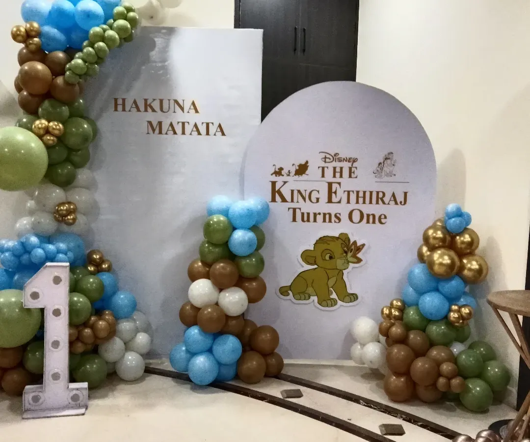 I bring beloved stories to life, like this "Lion King" theme for a first birthday party. The setup includes custom backdrops with "Hakuna Matata," a personalized circular sign, and balloon columns in jungle-inspired colors. The large light-up number '1' makes it clear this is for a milestone celebration.